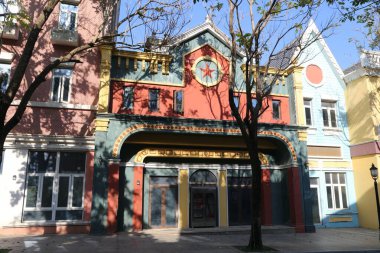 Kırmızı çatılı ve büyük yeşil kemerli bir bina. Bina boş ve bir sürü penceresi var.