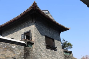 Geniş pencereli ve çatısı kırmızı çizgili bir bina. Bina tuğladan yapılmıştır ve geleneksel bir Asya tasarımına sahiptir.