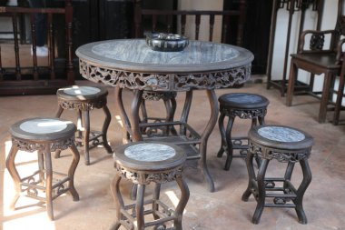 Altı ahşap tabure ve tepesinde bir kase olan yuvarlak bir masa. Masa taştan bir zemin ile çevrili.