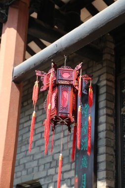 A red lantern with red tassels hanging from it is suspended from a building. The lantern is intricately designed and has a Chinese influence. The red color of the lantern clipart