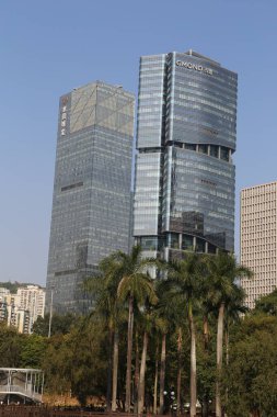 Önünde eşsiz bir tasarımı ve bir palmiye ağacı olan büyük, modern bir bina. Binanın birçok penceresi var, şık ve sofistike bir görünümü var.