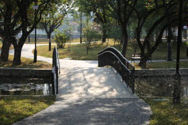 Parktaki göletin üzerinde bir köprü. Köprü yağmurdan ıslandı. Park boş.