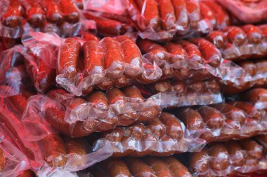 Plastik ambalajda bir yığın sosisli. Sosisliler üst üste yığılmış.