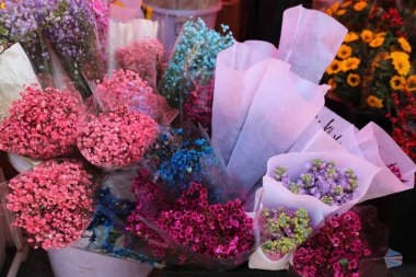 Bazıları pembe, bazıları mavi olmak üzere bir mağazada bir demet çiçek sergilenir.