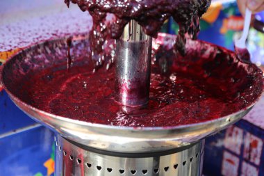 Kırmızı sıvıyla dolu gümüş bir kase. Kase bir masanın üzerinde ve içinde bir insan eli var.