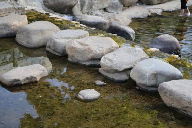 Kayalardan yapılmış köprüsü olan bir gölet. Su sakin ve berrak. Kayalar göletin etrafına dağılmış doğal ve huzurlu bir atmosfer yaratıyorlar.