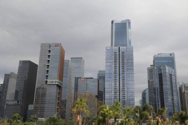 Ortasında büyük bir bina olan bir şehir silueti. Gökyüzü bulutlu ve binalar yüksek.