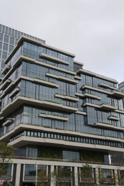 Yeşil çatısı ve birçok penceresi olan büyük, modern bir bina. Bina çok uzun ve parlak, çağdaş bir tasarıma sahip. Pencereler büyük.