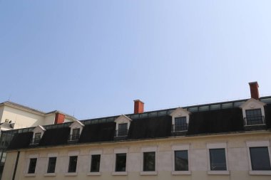 Bir sürü penceresi ve bacası olan bir bina. Baca kırmızı ve bina beyaz.