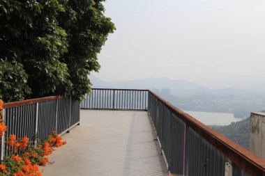 Tırabzanı, manzarası ve dağları olan bir yürüyüş yolu. Korkuluklar metalden yapılmıştır ve yürüyüş yolu betondan yapılmıştır.