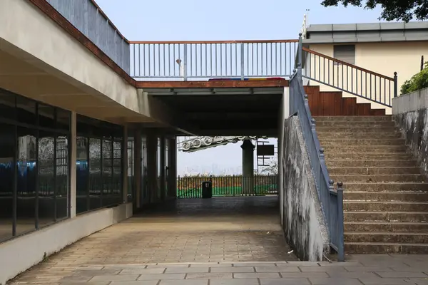 Uzun bir yolu ve merdivenleri olan büyük bir bina. Geçit boş ve merdivenler gri.