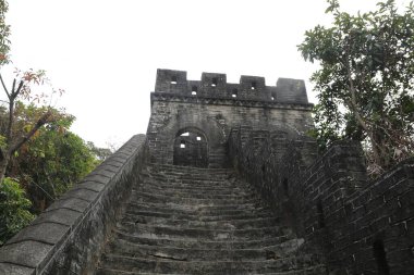 Üzerinde merdiven olan taştan bir duvar. Duvar yosunla kaplı ve merdivenler yıpranmış. Huzurlu ve huzurlu bir sahne.