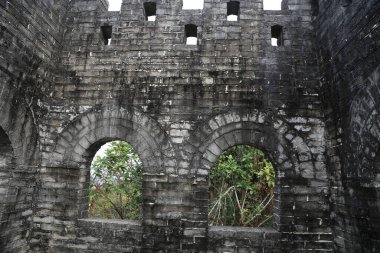 Yan tarafında iki pencere olan büyük bir taş bina. Pencereler açık, ışığın içeri girmesini ve içeriyi aydınlatmasını sağlıyor. Bina eski görünüyor ve bir tarih anlayışı var.