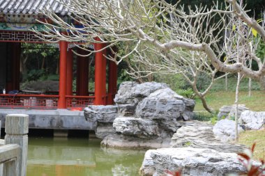 Önünde gölet olan taş bir duvar. Gölet kayalarla çevrili ve üzerinde bir köprü var. Köprü taştan yapılmıştır ve bir köşkün yakınındadır. Huzurlu ve huzurlu bir sahne.