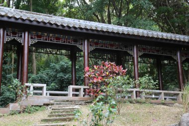 Kırmızı çatılı ve kırmızı süslemeli ahşap bir yapı. Çatı yapraklarla kaplı ve yapı ağaçlarla çevrili.