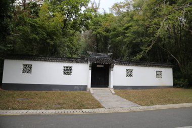 Her iki tarafında siyah kiremitler ve küçük pencereler olan antik bir Çin tarzı beyaz duvar var. Bir tarafındaki kapının ön cephesinde koyu gri bir renge oyulmuş dört kare şekli var..