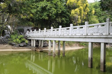 Arka planda ağaçlar olan bir köprü. Köprü beyaz ve çok detay içeriyor.