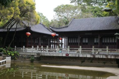 Her iki tarafında evler olan bir göletin üzerinde bir köprü. Evler ahşaptan yapılmış ve çatılardan sarkan kırmızı fenerler var. Sahnenin huzurlu ve huzurlu bir atmosferi var.