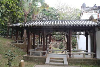 Çatısı ve bankları olan küçük bir avlu. Çatı kiremitlerden yapılmıştır ve banklar tahtadan yapılmıştır. Avlu ağaçlarla çevrili ve huzurlu bir atmosferi var.