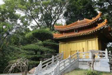 Altın çatılı ve beyaz tırabzanlı küçük bir bina. Bina ağaçlar ve çalılarla çevrili.