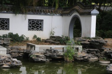 Taş köprüsü ve taş çeşmesi olan taş bir duvar. Çeşme yeşildir ve etrafında bazı bitkiler yetişir.