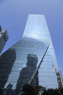 Bir sürü penceresi ve camında daha küçük bir binanın yansıması olan yüksek bir bina. Gökyüzü açık ve mavi