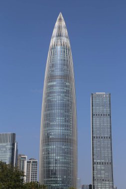 Çok uzun ve ince şekilli yüksek bir bina. Bina diğer binalar ve ağaçlarla çevrili.