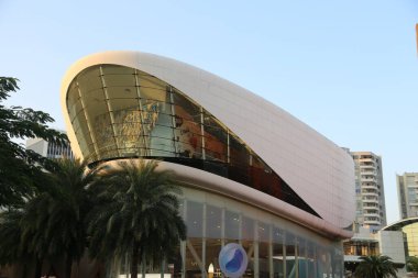 Kavisli çatılı ve geniş pencereli büyük bir bina. Bina beyaz ve mavi-beyaz bir tasarımı var.