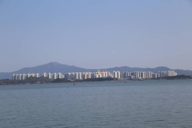 Önünde büyük bir su kütlesi bulunan bir şehir silueti uzaktan görülebilir. Gökyüzü berrak ve mavi, ve su sakin. Şehir olarak barış ve sükunet kavramı.