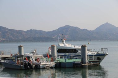 Bir tekne, diğer birkaç tekneyle birlikte rıhtıma yanaştı. Su sakin ve gökyüzü berrak.