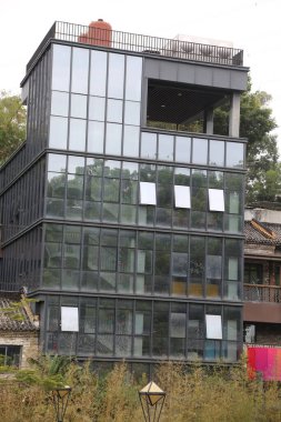 Bir sürü penceresi ve balkonu olan yüksek bir bina. Bina camdan yapılmış ve modern bir tasarımı var.