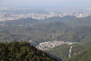 Wutong Dağı 'ndan şehrin manzarası, yeşil dağlar ve yüzeyinin yarısını kaplayan yoğun ormanlarla, bir tarafta yemyeşil bitkiler sergilenirken, diğer tarafta da aşağıdaki tepelerde yuva yapmış binalar görülüyor..