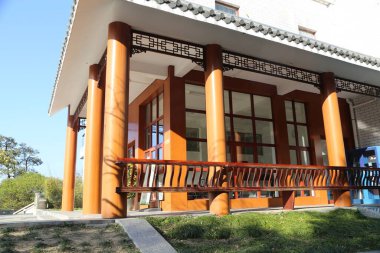 Üniversite binasının Çin esinlenilmiş yeni mimarisi her iki tarafında iki turuncu ahşap kolona sahip ve önünde ahşap korkuluklar olan açık bir balkon var. Arkaplanda siyah karolarla kaplı beyaz duvarlar var.