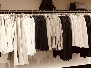 Üzerinde beyaz ve siyah gömlekler asılı bir elbise askısı. Beyaz gömlekler çoğunlukla sade ve siyah gömlekler daha desenli.