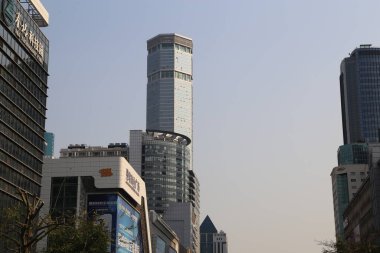 Shenzhen 'in merkezinde zarif ve modern bir tasarıma sahip, diğer binalarla çevrili yüksek bir bina bulunur. Gökyüzü açık ve mavi, bulutsuz, sakin bir atmosfer yaratıyor..