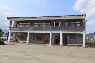 Gri tuğlalar ve beyaz fayanslardan yapılmış dış görünüşü olan iki katlı kırsal bir bina, büyük düz beton bir zeminde orta zemine kurulmuş. Yapıda ön girişinde üç sütun ve her iki duvar boyunca dört pencere yer alıyor..