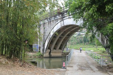 Taş köprü, her iki taraftaki bambu ormanları ve pirinç tarlalarıyla çevrili bir şehir parkının ortasında yer almaktadır. Alttaki zemin, girişe giden beton patikalara dönüştürülmüş..