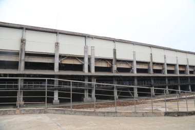 Açık çatılı büyük bir dikdörtgen bina, üç sıra sütun ve iki katta çelik parmaklıklar var. Duvarlar beyaz metal panellerden yapılmış..