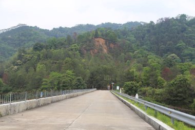 Baraja giden yol çok uzun, her iki tarafında yeşil dağlar ve ormanlar var. Arkasındaki beton duvarın bazı yerlerinde şiddetli yağmur ya da deprem nedeniyle oluşan hareket sonucu oluşan görünür çatlaklar var..