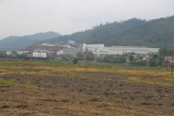 Arkasında bir sürü bina ve tepe olan bir kasaba. Tepe ağaçlarla kaplı.