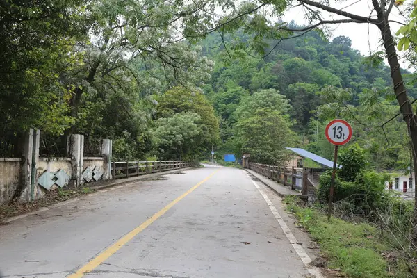 Yol eski bir köprünün sol tarafında yer alıyor, bu yol Çin 'in kırsal kesimindeki küçük bir kasabaya çıkıyor. Her iki taraftaki ağaçlar ve yemyeşil bitki örtüsü doğal güzelliğine katkıda bulunur..