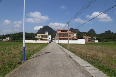 Sağ tarafında bir ev olan bir yol. Ev kahverengidir. Yolun sol tarafında bir direk var.