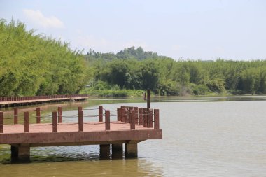 Tropik iklimde yeşil ağaçlar ve bambu ormanlarıyla çevrili, göl kıyısında bir halk parkı. İskele, su yüzeyine bakan ahşap korkuluklardan oluşan kırmızı betondan yapılmıştır..