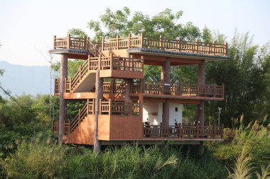 İki katlı ahşap bina, yaklaşık beş metreye üç metrelik bir alanı ve her katta küçük otel odaları olarak tasarlanmış balkon korkulukları bulunan ormanda yer alıyor. Üst platformda rahatlamak için bir açık hava çay seti var..