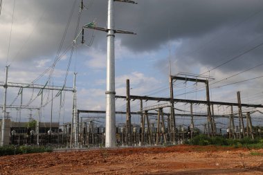 Bir sürü elektrik hattı ve direği olan bir elektrik santrali. Gökyüzü bulutlu.