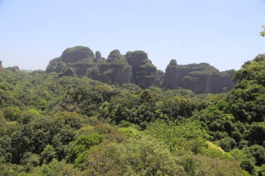 Dağın tepesi yeşil bitki örtüsüyle kaplı ve önünde çok uzaklardan görülebilen eski bir kayalık var. Tüm manzara yoğun ormanları ortaya çıkarıyor.