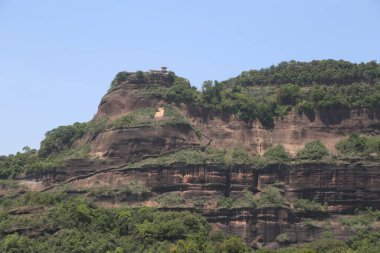 Çin 'in güney bölgesinde, zirvede bir tapınağı olan, yemyeşil ve tabanında düz bir zemin bulunan bir tepe. Alt kısmı kayalıklara benziyor..