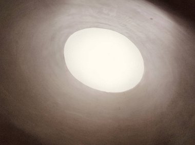 Beyaz tavandaki oval bir deliğin ortasında yukarıdan ışık süzülüyor. Açılış yuvarlaktır ve pürüzsüz bir yüzeyi vardır. Etrafı karanlıktır, bu yüzden kenarlarında sadece küçük detaylar görülebilir..