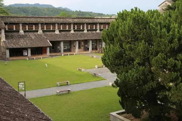 Çin okul binasının açık yeşil çimenliği antik stil bir avluyla çevrili. Beton zemin bilim adamlarının badminton oynadığı ve önünde futbol oynayan insanların oynadığı eski tarz ahşap banklar var..