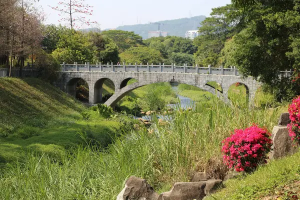 Nehrin üzerinde sağ tarafında çiçek olan bir köprü. Köprü taştan yapılmıştır.